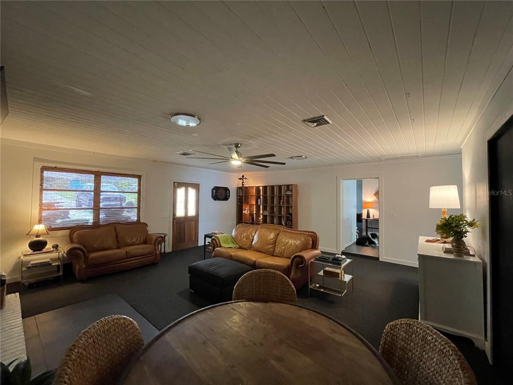 A living room features a wood-paneled ceiling, dark carpeting, and two leather sofas — 879 S TERRACE DRIVE, EAGLE LAKE, FL