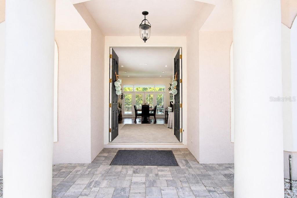 A view through an open double door into a dining room with large windows — 9606 CAMBERLEY CIRCLE, ORLANDO, FL
