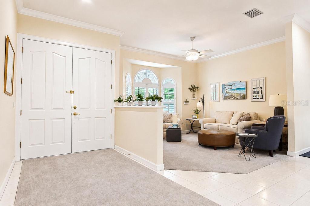 A foyer with double doors opens into a living room featuring a half-wall and carpet — 9606 CAMBERLEY CIRCLE, ORLANDO, FL