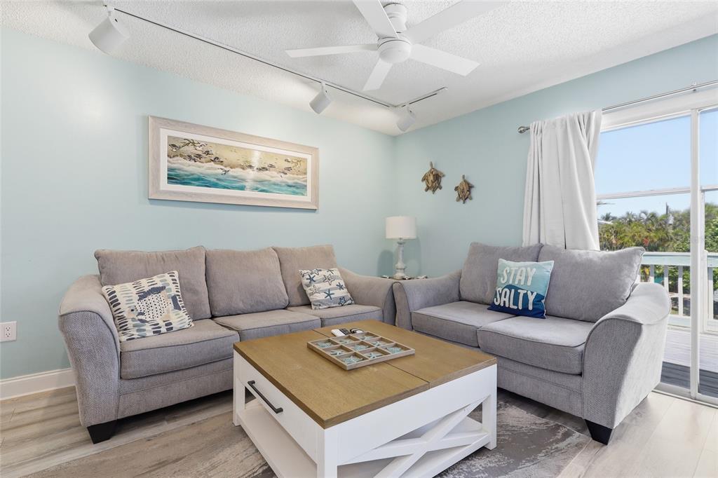 An elevated gray house with a white deck and a covered parking area underneath — 207 71ST STREET UNIT E, HOLMES BEACH, FL
