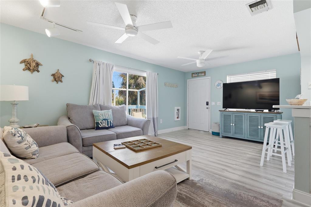 A living room features two gray sofas, a wooden coffee table, and light blue walls — 207 71ST STREET UNIT E, HOLMES BEACH, FL