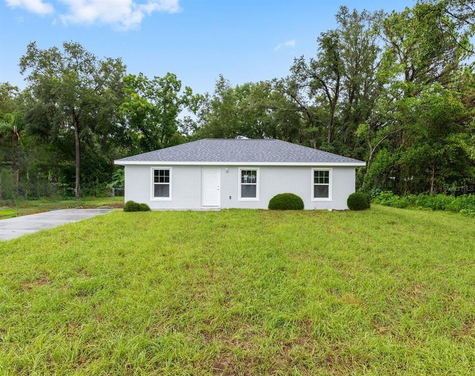 A single-story gray house with a white door, new windows, and a green lawn — 8304 SW 202ND AVENUE, DUNNELLON, FL