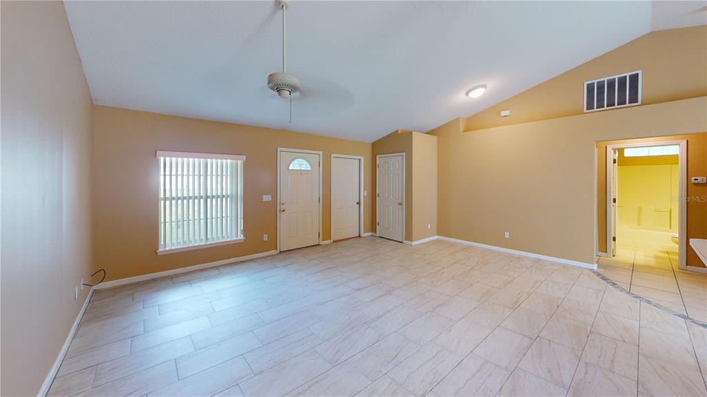 A room with tan walls, light-colored tile flooring, a vaulted ceiling, and a ceiling fan — 18 LLOLEETA PATH, PALM COAST, FL