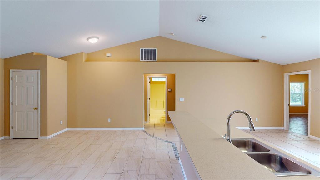 A kitchen with a breakfast bar and double sink overlooks a room with tiled floors — 18 LLOLEETA PATH, PALM COAST, FL