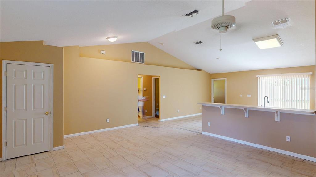 An open-concept living area features vaulted ceilings, tan walls, and light-colored tile flooring — 18 LLOLEETA PATH, PALM COAST, FL