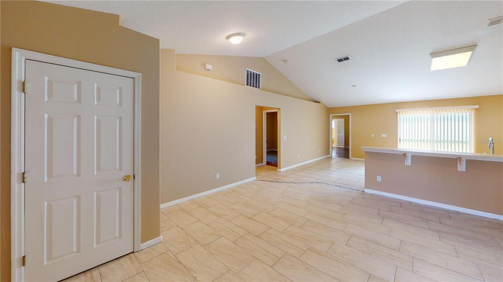 An interior view of a room with beige walls, tiled floors, and a vaulted ceiling — 18 LLOLEETA PATH, PALM COAST, FL