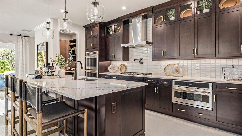 A modern kitchen features dark wood cabinetry, a large marble-topped island, and stainless steel appliances — 545 HAMMOCK OAKS BOULEVARD, LADY LAKE, FL