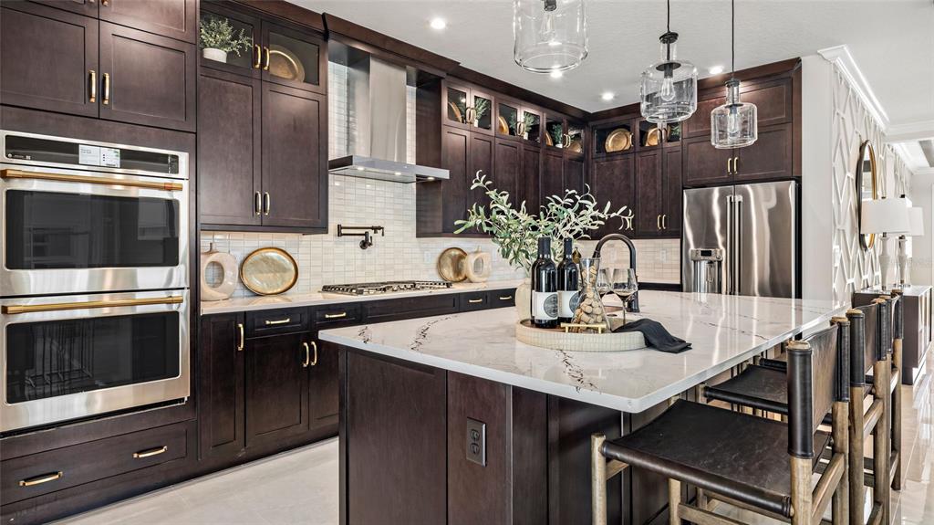 A modern kitchen features dark wood cabinetry, a marble-topped island, and stainless steel appliances — 545 HAMMOCK OAKS BOULEVARD, LADY LAKE, FL