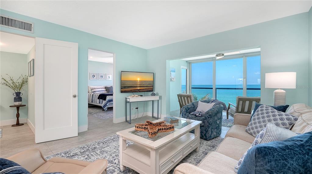 A living room with light blue walls, a beige sofa, and a view of the ocean — 9000 BLIND PASS ROAD UNIT 303, SARASOTA, FL