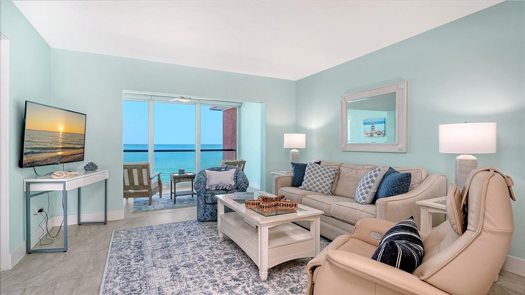 A living room with light blue walls, a beige sofa, and a view of the ocean — 9000 BLIND PASS ROAD UNIT 303, SARASOTA, FL