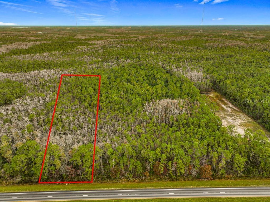 An aerial view shows a rectangular plot of wooded land outlined in red near a highway — 20617 E COLONIAL DRIVE, CHRISTMAS, FL