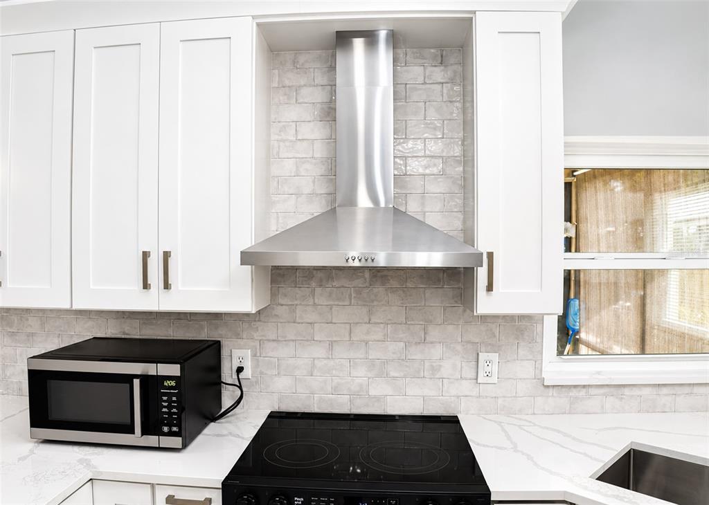 A kitchen with white cabinets and marble-patterned countertops overlooks a living room with tiled floors — 2609 MILL RUN BOULEVARD, KISSIMMEE, FL
