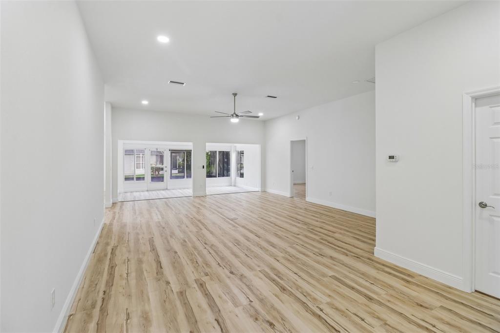 An empty room with white walls, light wood-look flooring, a ceiling fan, and a front door — 207 DESOTA COURT, THE VILLAGES, FL