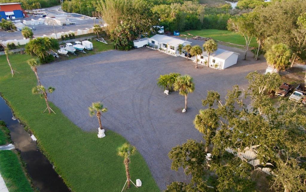 A gravel driveway leads toward a Kora Motorsports sign and trees on a sunny day — 1322 N PINELLAS AVENUE, TARPON SPRINGS, FL