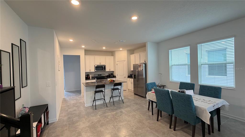 An open-concept kitchen and dining area features white cabinets, stainless steel appliances, and tile flooring — 4125 PINO STREET, APOPKA, FL