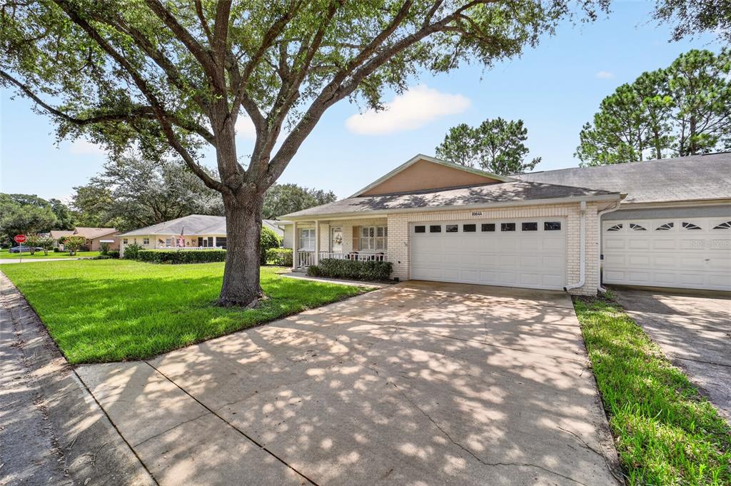 A single-story brick house with a front porch, attached garage, and a green lawn — 8964 SW 95TH STREET UNIT A, OCALA, FL