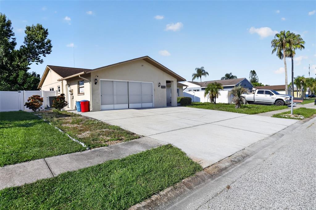 A single-story house with a concrete driveway, a two-car garage, and a white privacy fence — 3104 DOLE STREET, HOLIDAY, FL