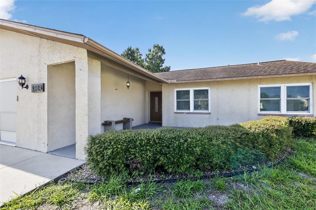 A single-story house exterior features a covered entryway, a garage, and a landscaped front yard — 3104 DOLE STREET, HOLIDAY, FL