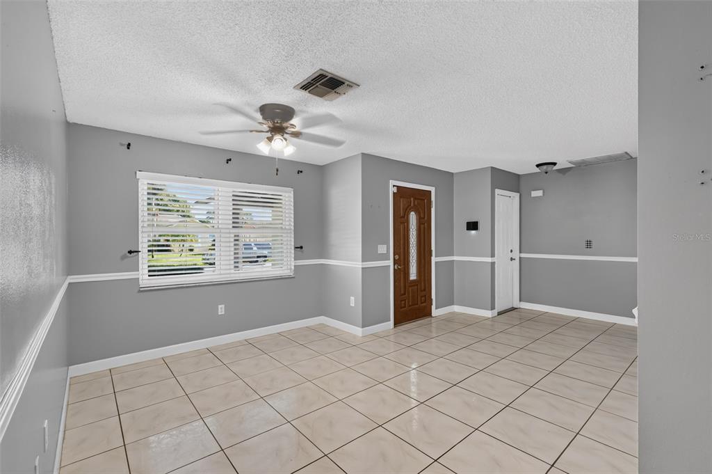 A room with gray walls, white chair rail molding, tile flooring, and a ceiling fan — 3104 DOLE STREET, HOLIDAY, FL