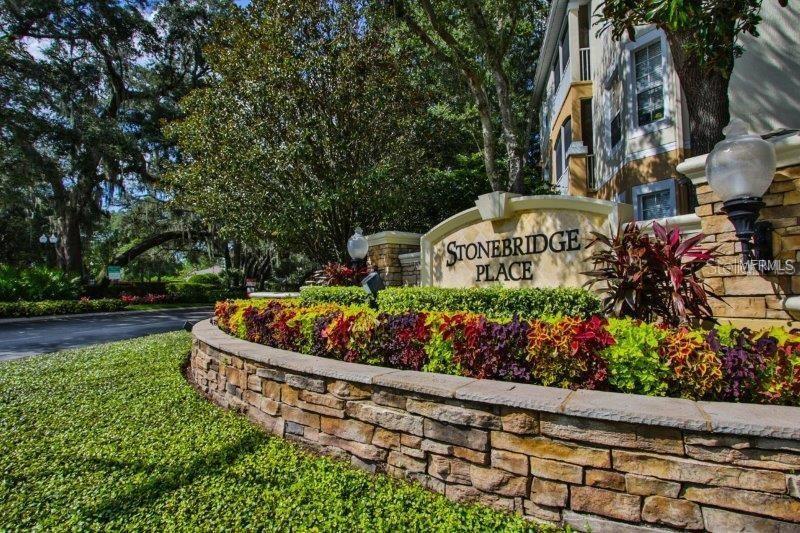 A stone wall and colorful landscaping surround the Stonebridge Place community entrance sign — 6214 STEVENSON DRIVE UNIT 201, ORLANDO, FL