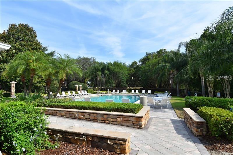 An outdoor swimming pool surrounded by lounge chairs, stone walls, and lush landscaping — 6214 STEVENSON DRIVE UNIT 201, ORLANDO, FL