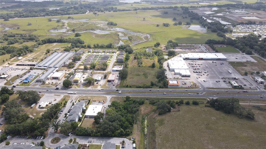 An aerial view shows a commercial area with buildings, parking lots, and surrounding green space — US HIGHWAY 301, DADE CITY, FL
