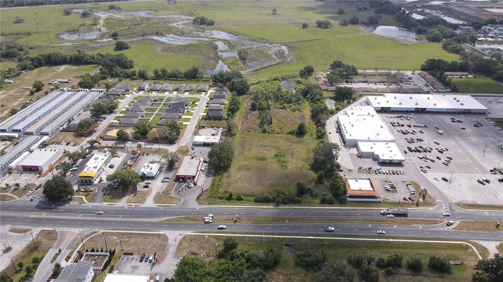 An aerial view shows a vacant lot situated between a commercial shopping center and residential housing — US HIGHWAY 301, DADE CITY, FL