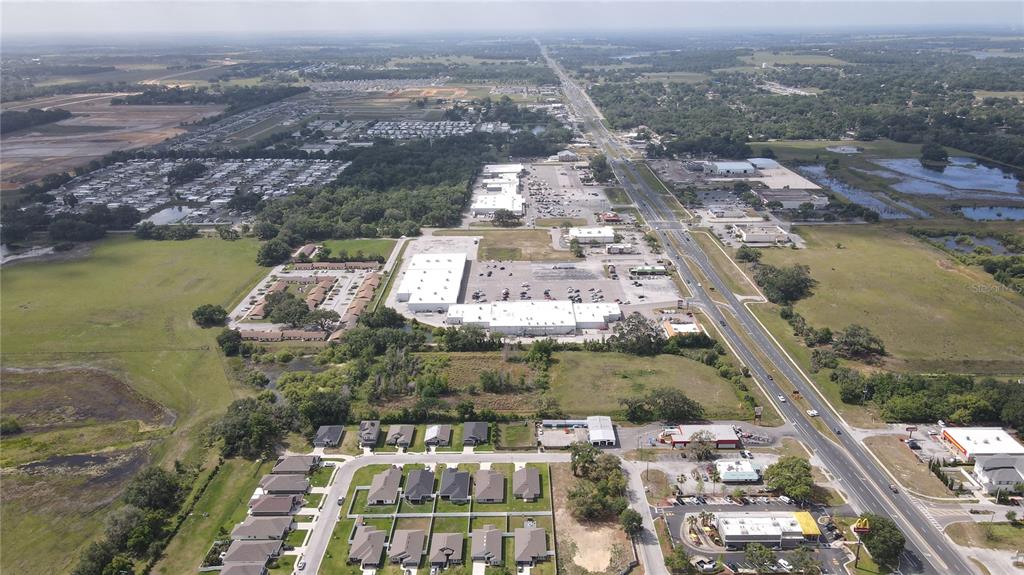 An aerial view shows a commercial shopping center, residential neighborhoods, and a highway in Florida — US HIGHWAY 301, DADE CITY, FL
