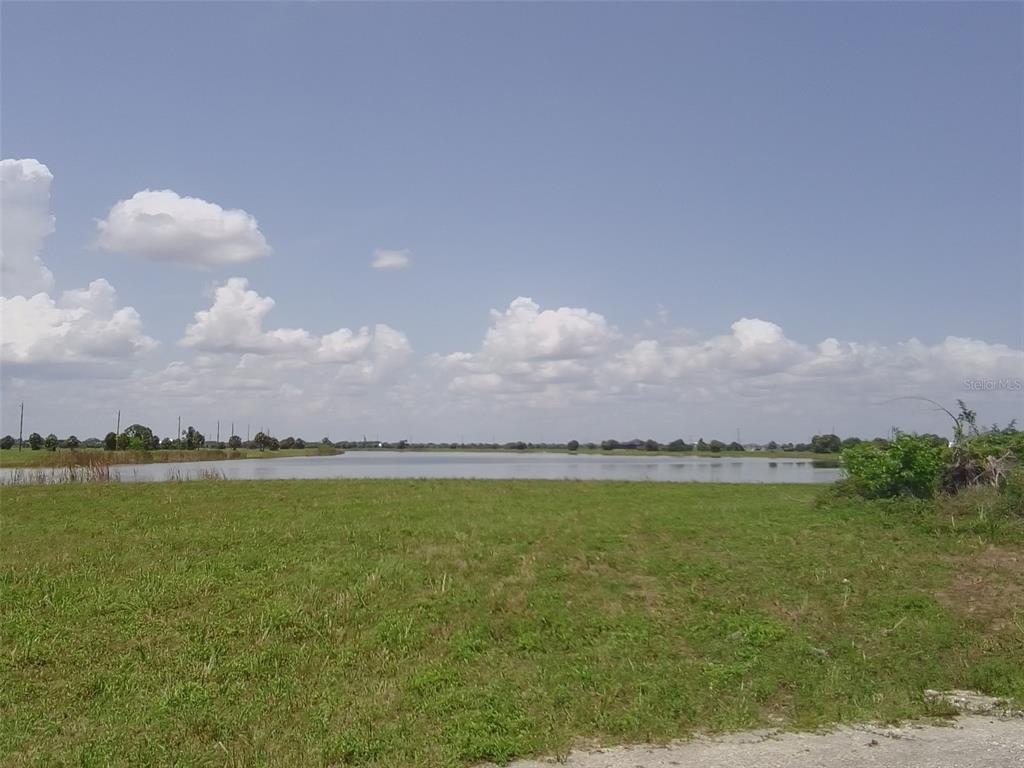 A grassy field leads to a large lake under a blue sky with clouds — 45 SUNFLOWER DRIVE, PLACIDA, FL
