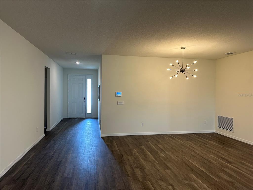 An entryway leads to a dining area featuring a sputnik chandelier and wood-look flooring — 3272 ARCH AVENUE, ORMOND BEACH, FL