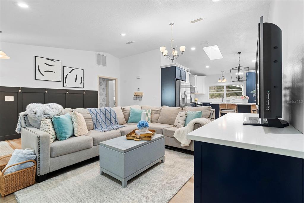 A living room features a large sectional sofa, a light blue coffee table, and dark paneling — 1049 W NEW YORK AVENUE, ORANGE CITY, FL