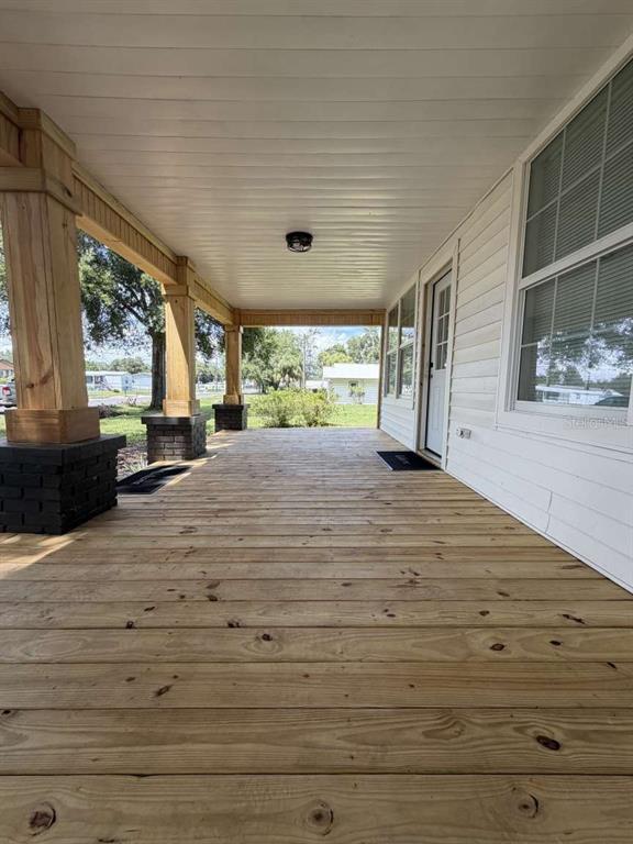A wooden porch features thick support columns with dark brick bases and white siding — 10120 ALAFIA STREET, GIBSONTON, FL