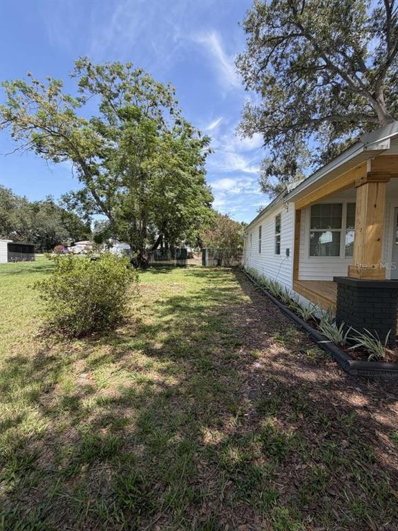 A side view of a white house with a wooden porch and a grassy yard — 10120 ALAFIA STREET, GIBSONTON, FL