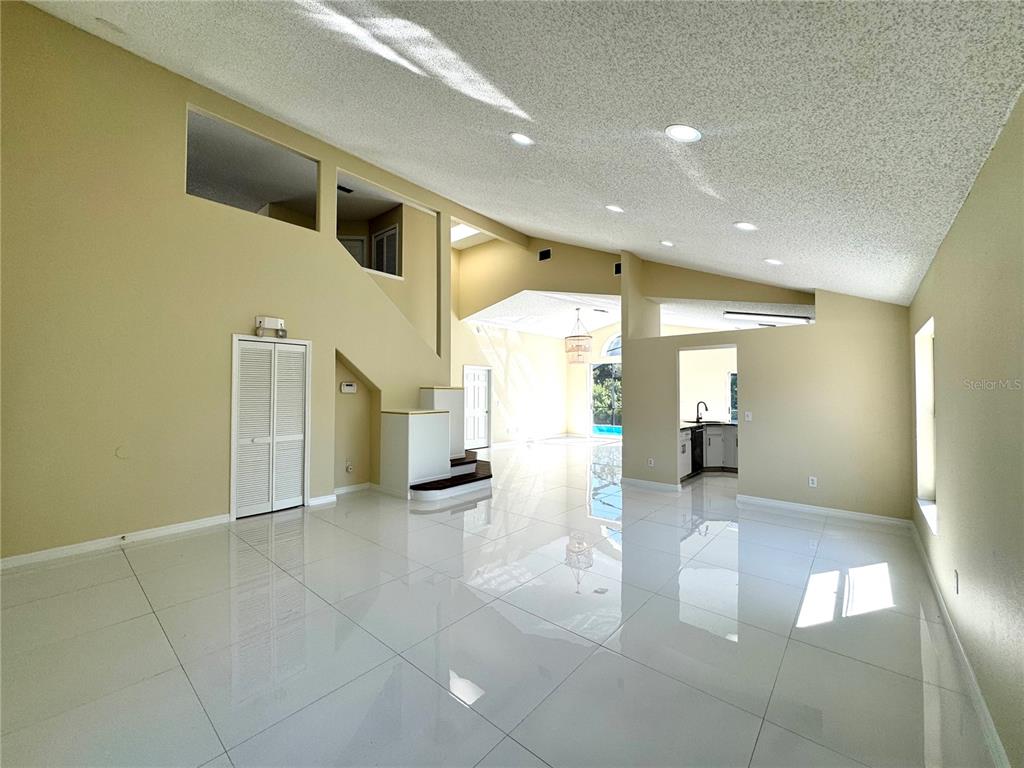 A spacious living area features high vaulted ceilings, white tile flooring, and recessed lighting — 2985 VISCOUNT CIRCLE, KISSIMMEE, FL