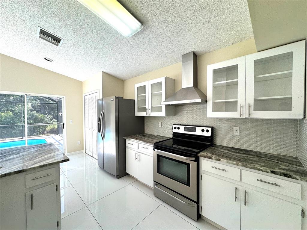 A kitchen features white cabinets, stainless steel appliances, granite countertops, and a view of a pool — 2985 VISCOUNT CIRCLE, KISSIMMEE, FL