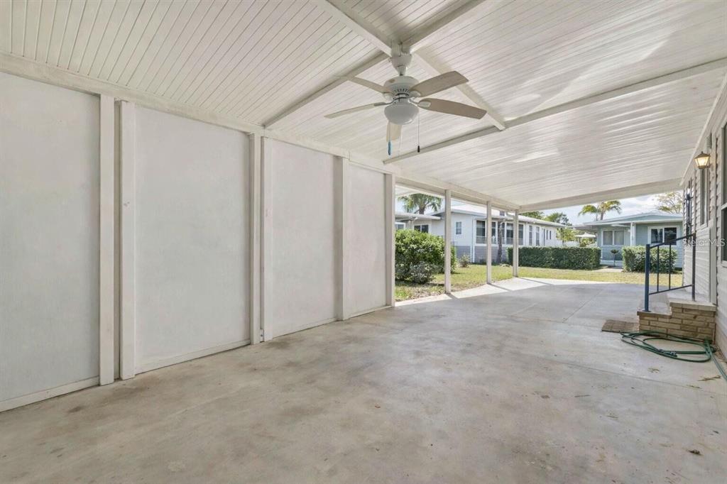 A covered concrete carport with a ceiling fan and white paneled walls — 10303 BURNT STORE ROAD UNIT 54, PUNTA GORDA, FL