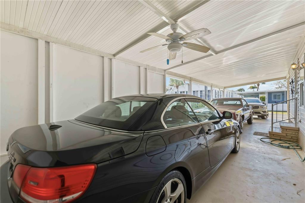 A black car is parked under a covered carport with a ceiling fan — 10303 BURNT STORE ROAD UNIT 54, PUNTA GORDA, FL