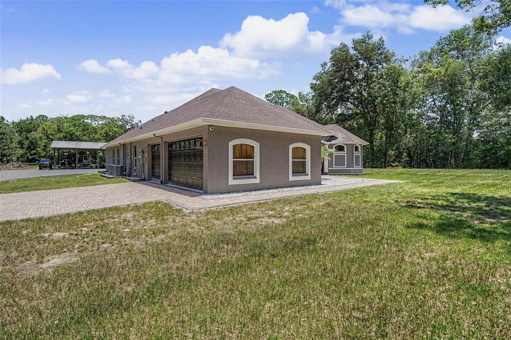 The exterior of a tan house with a paved driveway and a detached garage — 10933 PINTO DRIVE, HUDSON, FL