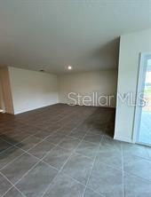 An empty room with light-colored walls and large gray floor tiles — 16953 NW 176TH WAY, ALACHUA, FL
