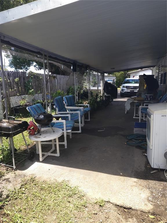 A screened-in porch features wicker furniture with blue patterned cushions and potted banana plants — 37748 MARKLAND AVENUE, ZEPHYRHILLS, FL