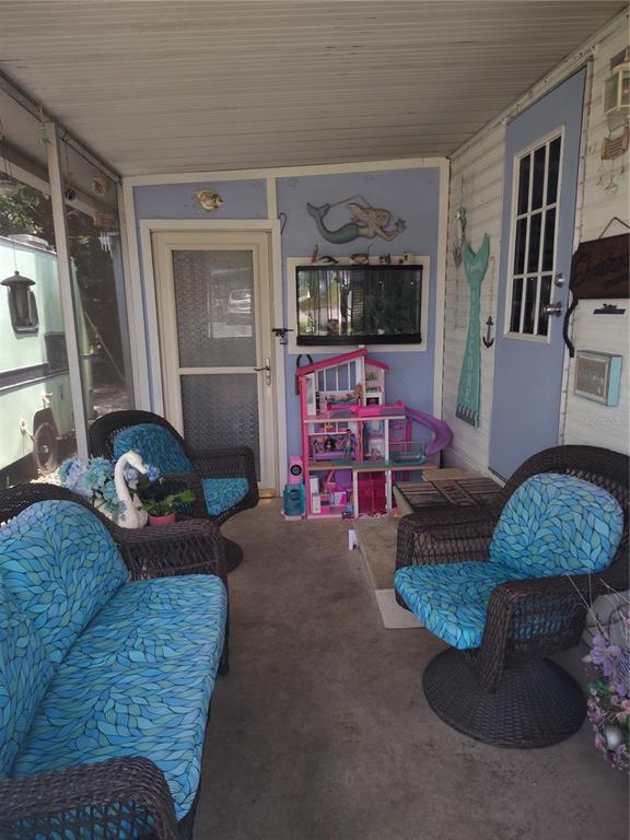 A living room features a beaded chandelier, a sofa with a cat, and a television — 37748 MARKLAND AVENUE, ZEPHYRHILLS, FL