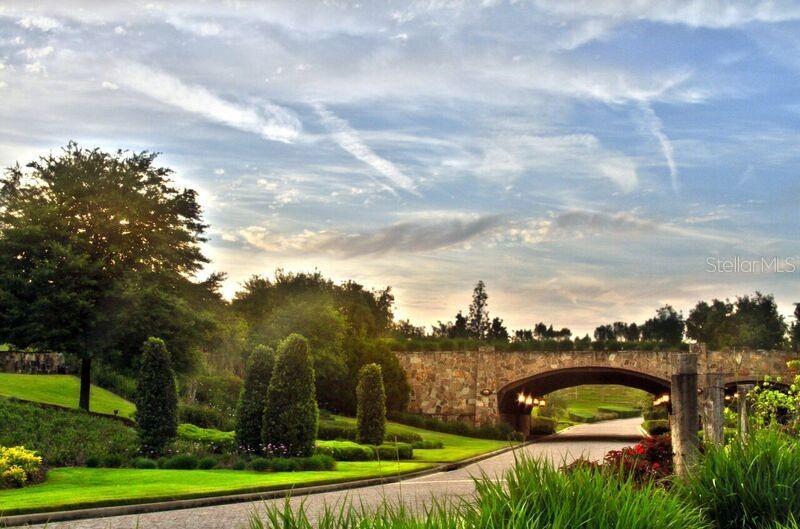A stone bridge arches over a paved driveway surrounded by landscaped lawns and trees — 16122 TRIVOLI CIRCLE, MONTVERDE, FL
