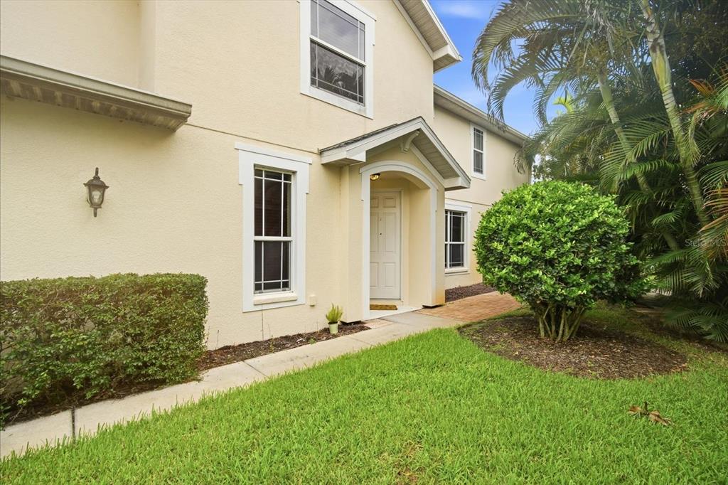 A two-story house exterior with a beige stucco facade, front entrance, and landscaped lawn — 368 HARBOR RIDGE DRIVE, PALM HARBOR, FL