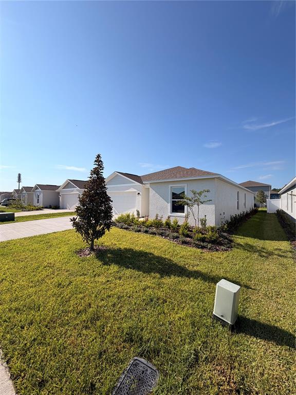 A single-story house with a light-colored exterior and a green lawn under a clear sky — 1912 PINE MEADOWS GOLFCOURSE RD, EUSTIS, FL