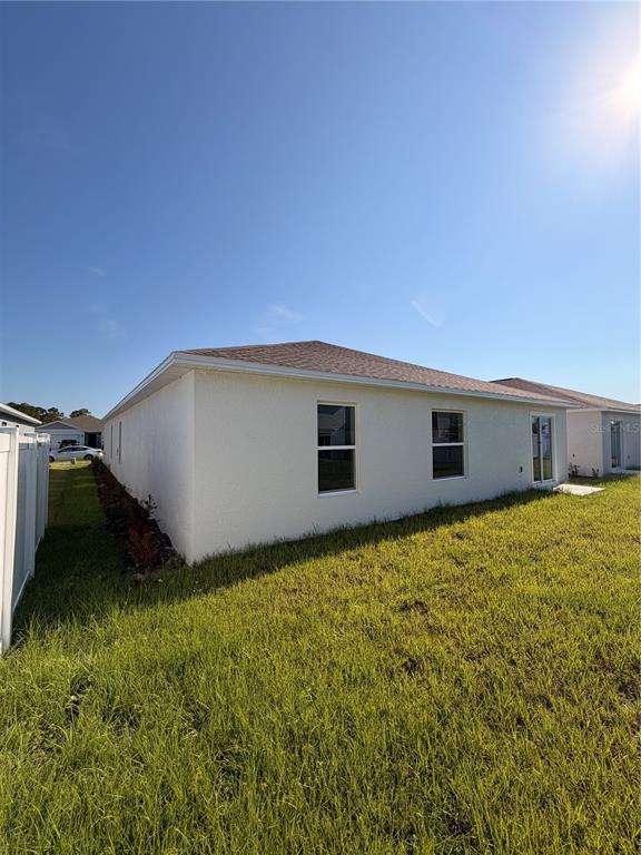 The exterior view shows the back of a light-colored house with a grassy yard — 1912 PINE MEADOWS GOLFCOURSE RD, EUSTIS, FL