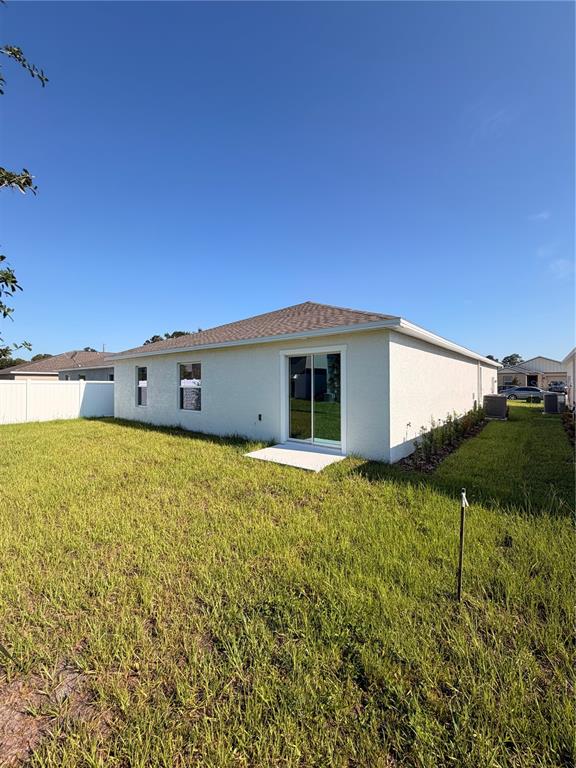 The exterior of a light-colored house features a sliding glass door and a grassy yard — 1912 PINE MEADOWS GOLFCOURSE RD, EUSTIS, FL