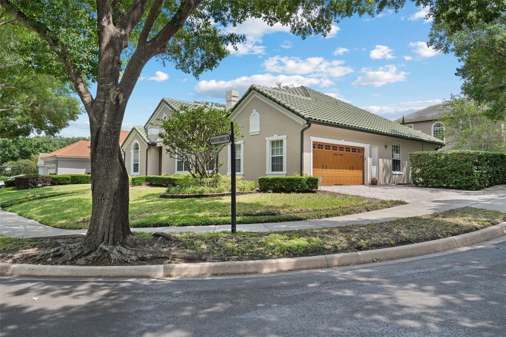 A tan single-story house with a tile roof and a wooden garage door on a corner — 7698 MOUNT CARMEL DRIVE, ORLANDO, FL
