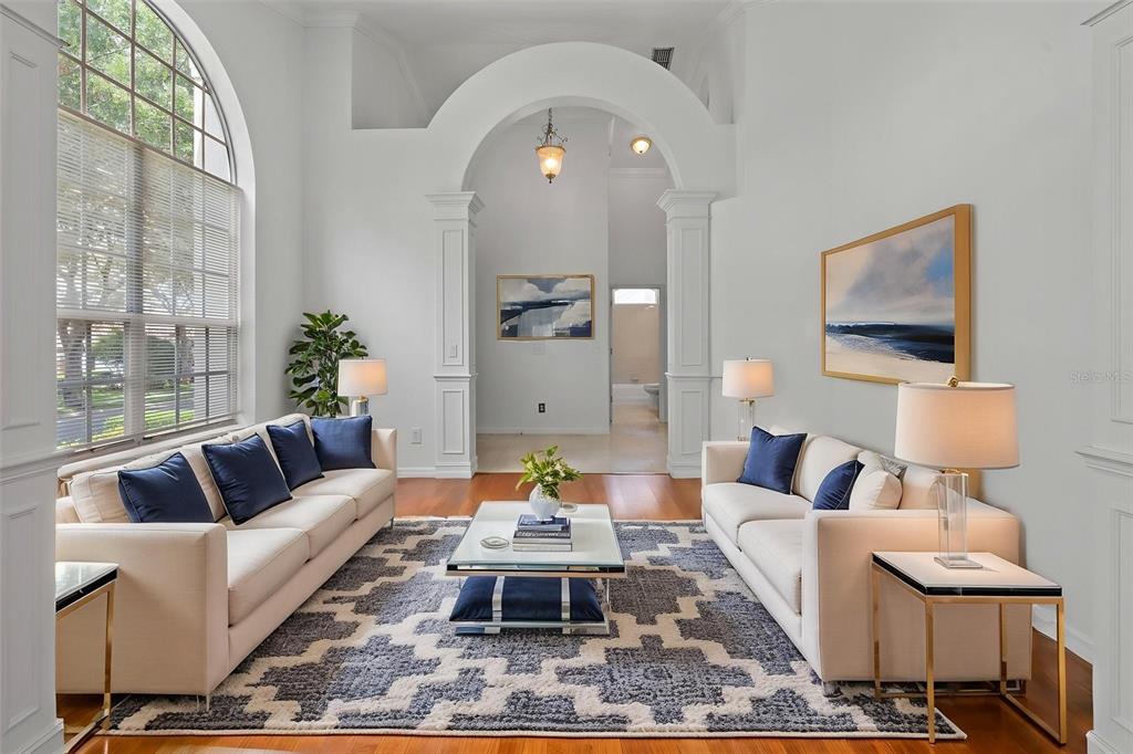 A living room features two white sofas, a patterned rug, and a large arched entryway — 7698 MOUNT CARMEL DRIVE, ORLANDO, FL