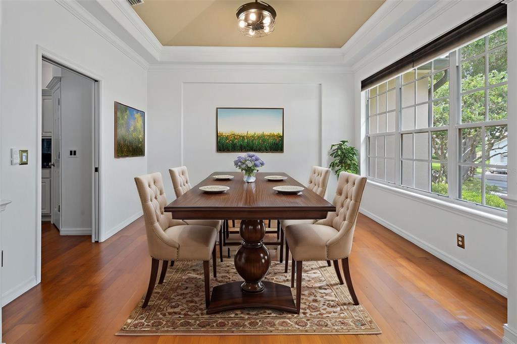 A dining room with a wooden table, tufted chairs, a tray ceiling, and large windows — 7698 MOUNT CARMEL DRIVE, ORLANDO, FL