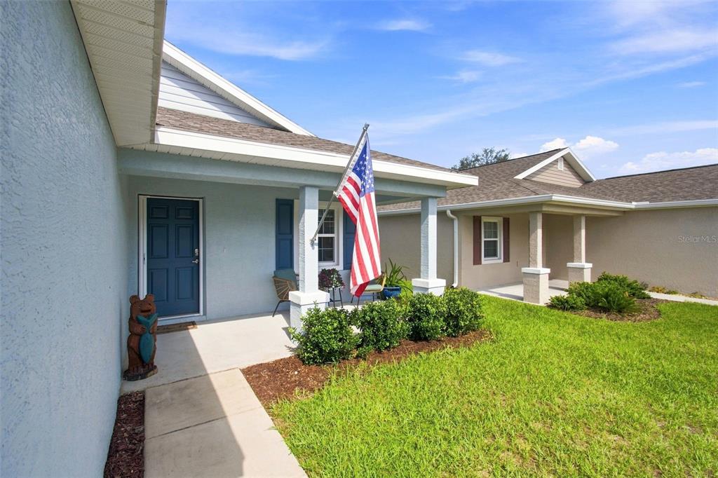 A view of a house exterior featuring a covered front porch and an American flag — 10535 S DREW BRYANT CIRCLE, FLORAL CITY, FL